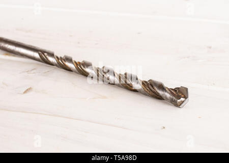 One whole metal drill work item on white wood Stock Photo