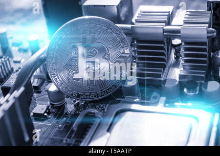 Silver bitcoin on the motherboard, closeup view. Business concept of digital cryptocurrency. Blockchain technology, bitcoin mining concept Stock Photo