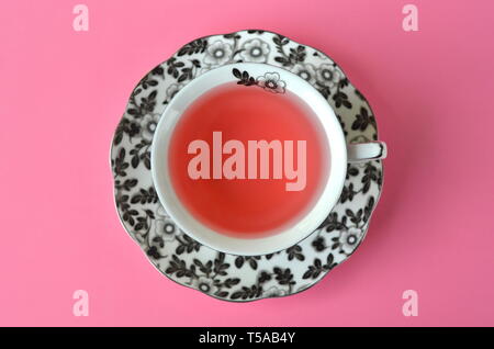 Fruit tea in a fine black and white floral porcelain cup on vivid pink background with copy space Stock Photo