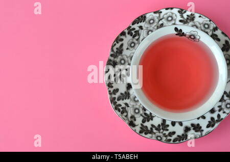 Fruit tea in a fine black and white floral porcelain cup on vivid pink background with copy space Stock Photo