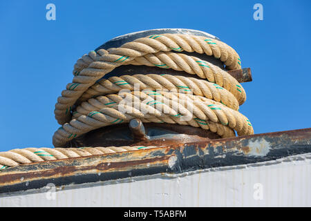 Mooring rope coiled around a bollard at a steel ship Stock Photo