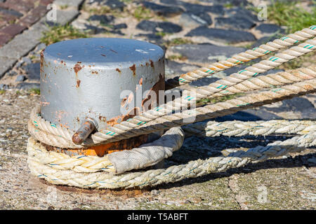Mooring rope coiled around a bollard Stock Photo