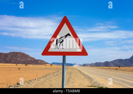 Giraffes crossing warning road sign placed in the desert of Namibia Stock Photo