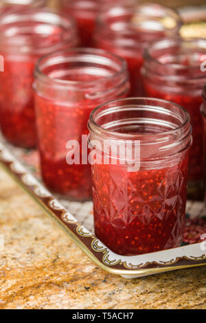 Jars filled with raspberry jam. Fill your awaiting (sanitized) jars immediately to within 1/2 inch of tops prior to putting lids on them. (PR) Stock Photo