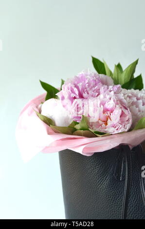 Light pink peony bouquet wrapped in tissue paper in tote bag with copy space Stock Photo