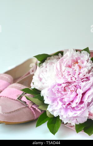 Light pink suede leather ballerina flats shoes with blush pink peonies bouquet wrapped in a tissue paper with copy space Stock Photo