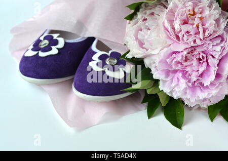 Purple violet suede leather ballerina flats shoes with blush pink peonies bouquet wrapped in a tissue paper with copy space Stock Photo