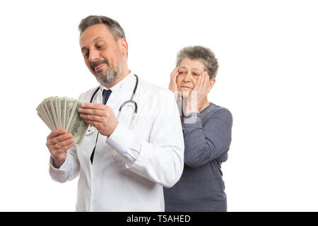 Greedy medic man counting dirty money with patient looking from behind and making worried expression and gesture touching face isolated on white Stock Photo