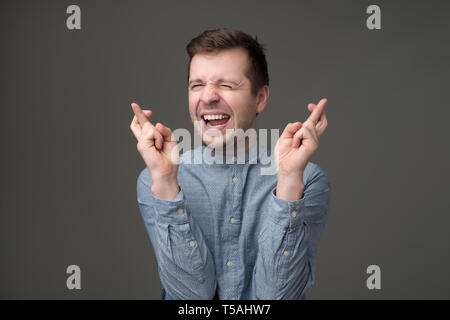 Funny young man hoping wishing for good luck crossing fingers. Stock Photo