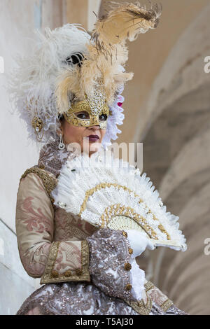 Masked woman wearing traditional Venetian costume holding fan, Venice carnival, Italy Stock Photo