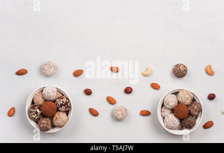 Healthy energy balls  in the ceramic  bowls and nuts scattered on a light surface. Snacks are tasty, sweet, no bake ,gluten free . Stock Photo