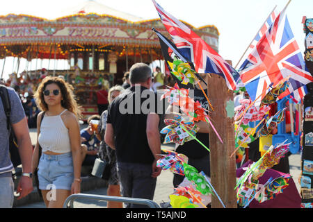 Coloured flags standing in a shop in front of the carousel. Brighton, UK Stock Photo