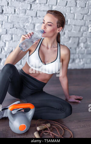 Young caucasian 20s woman drinking water from bottle after workout Stock Photo