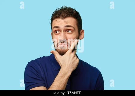 unhappy frustrated male touching his chin while thinking and looking with serious and worried look at somewhere. feeling, emotion, offence, apathy, indifference Stock Photo