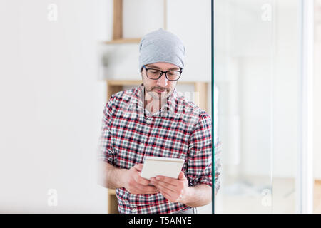 Modern businessman using digital tablet next to glass office door. Stock Photo