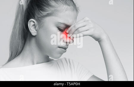 Sad woman holding her nose because sinus pain Stock Photo