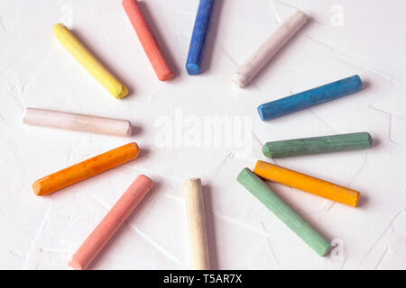 row of mixed color of used chalk pastel sticks crayon sun rays circle isolated on white background. Selective soft fokus. Stock Photo