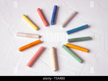 row of mixed color of used chalk pastel sticks crayon sun rays circle isolated on white background. Selective soft fokus. Stock Photo