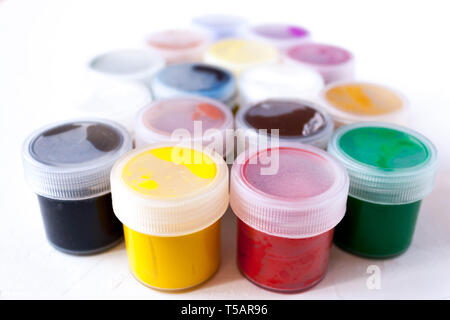many plastic jars with multy-colored gouache or acrylic paints side view on a light white background. Selective soft fokus. Stock Photo