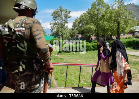 Anantnag, Jammu and Kashmir, India. 23rd Apr, 2019. An Indian paramilitary man seen standing on guard as Kashmiri voters seen entering a polling station in Anantnag, South Kashmir.On the third phase of India's Parliamentary elections, Indians went to polls amid complete shut down and internet gag. Credit: Idrees Abbas/SOPA Images/ZUMA Wire/Alamy Live News Stock Photo