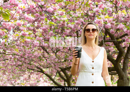 Greenwich, United Kingdom. 23rd April, 2019. Londoner Lizzie Cooper pauses to enjoy the cherry blossom in Greenwich Park. The popular avenue of cherry blossom in Greenwich Park, south east London, continues to draw visitors. Rob Powell/Alamy Live News Stock Photo