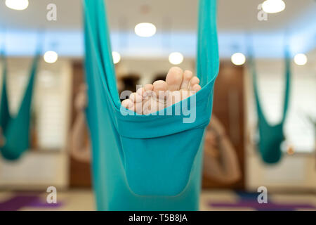 Closeup legs in hammock for fly yoga exercises. Woman doing fly yoga stretching exercises in gym. Fit and wellness lifestyle. Stock Photo