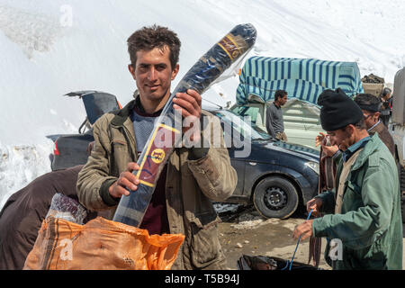 Smuggler Taking Iraqi Cloth Out Of Bag In Uraman Valley Bazaar in Winter, Kurdistan Province, Iran