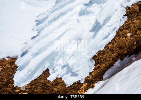 A wave of rime ice, or hoar frost, arcs out from the red rock near the summit of the volcano Mount Shasta in northern California. Stock Photo