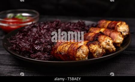 Fried homemade grilled sausages or chevapchichi with stewed sauerkraut and tomato sauce on a wooden rustic background. Stock Photo