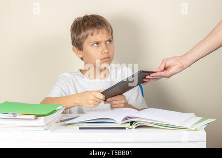 Video games addiction. Mother taking tablet away from the kid hands Stock Photo