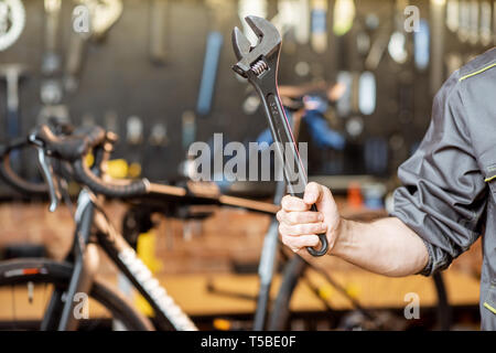Repairman holding cleavage key in the bicycle workshop, close-up view Stock Photo