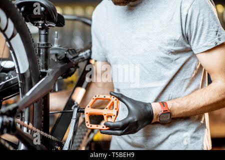 Repairman installing new pedals on a mountain bicycle at the workshop Stock Photo