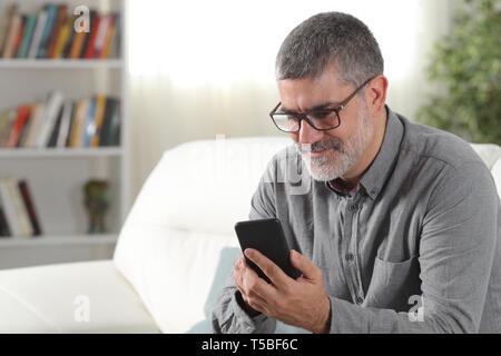 Happy mid aged man using a smart phone at home Stock Photo