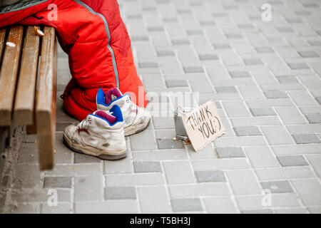 Beggar asking some money with cup and thank you cardboad on the street, close-up view Stock Photo