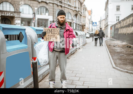 Portrait of a depressed homeless beggar with cardboard begging some money on the street in the city Stock Photo