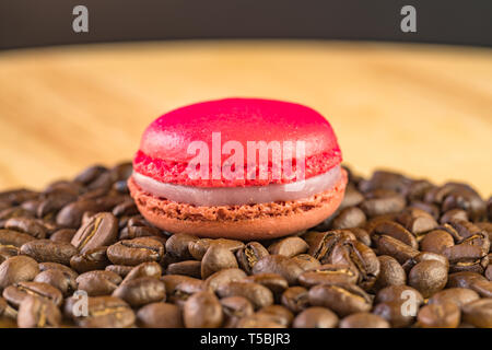 Macaroon on a pile of coffee beans on a wooden table Stock Photo