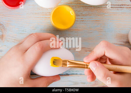 Preparation for Easter set for dyeing eggs on rustik background with plate of candy children hands, babycraft handmade Easter eggs Stock Photo