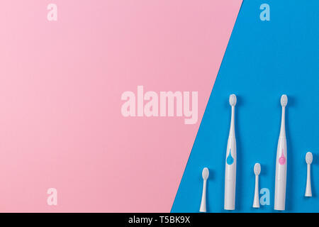 Two electric toothbrushes with three brush heads on blue and pink background. Top view Stock Photo