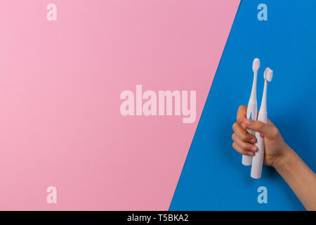 Kid hands with electric toothbrushes on blue background Stock Photo