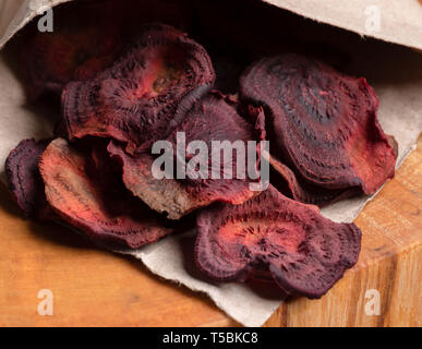 Close-up homemade beetroot chips in paper bag on wooden cut.  Stock Photo