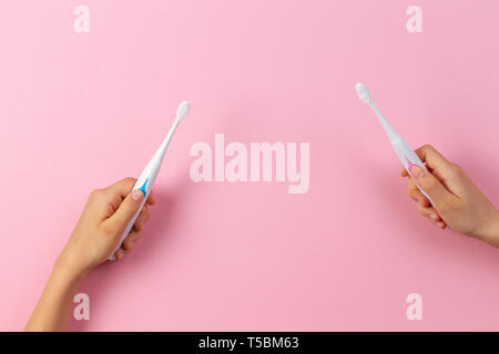 Kid hands with electric toothbrushes on pink background Stock Photo