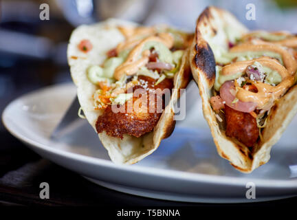 Close up of a fried walleye fish taco with lettuce, salsa, onion, tomato and sauce and shallow depth of field Stock Photo