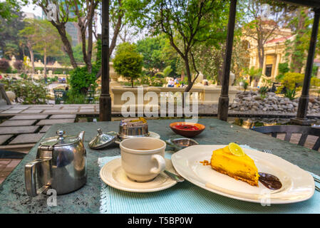 KATHMANDU, NEPAL - MARCH 30, 2019: Teatime with a piece of cheesecake and a cup of white tea in a recently beautifully renovated garden Stock Photo