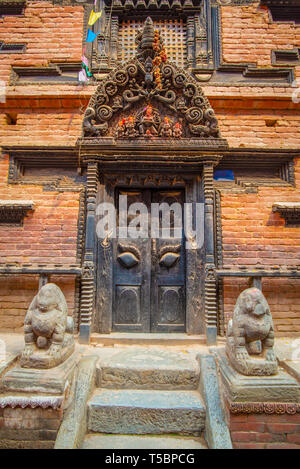 Old ornamented newari style door taken during a sunny afternoon in the historical center of Bhaktapur, Nepal Stock Photo