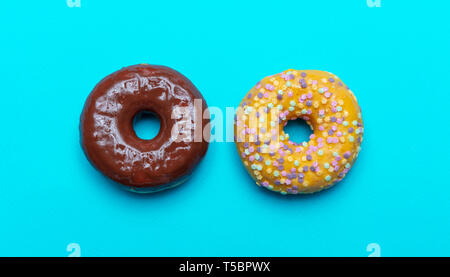 Two donuts chocolate and vanilla isolated on blue color background, top close up view Stock Photo