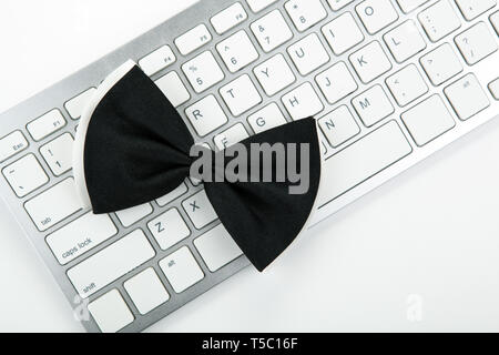 black bow-tie on a white computer keyboard top view Stock Photo