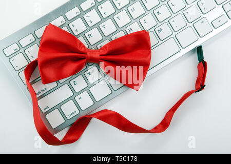 red bow-tie on a white computer keyboard top view Stock Photo