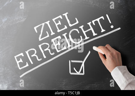 words ZIEL ERREICHT, German for goal accomplished,  with checkmark on blackboard Stock Photo