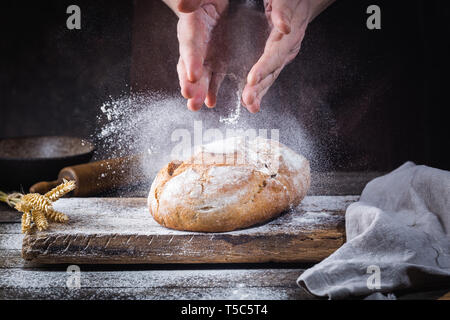 Baker cooking bread. Man slaps flour over the dough. Man's hands Making bread Stock Photo