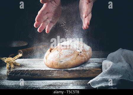 Baker cooking bread. Man slaps flour over the dough. Man's hands Making bread Stock Photo